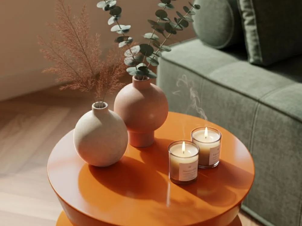 Gros plan en plongée d'un plateau laqué orange brillant, avec deux vases et deux bougies posés dessus et le reflet du parquet sur la laque
