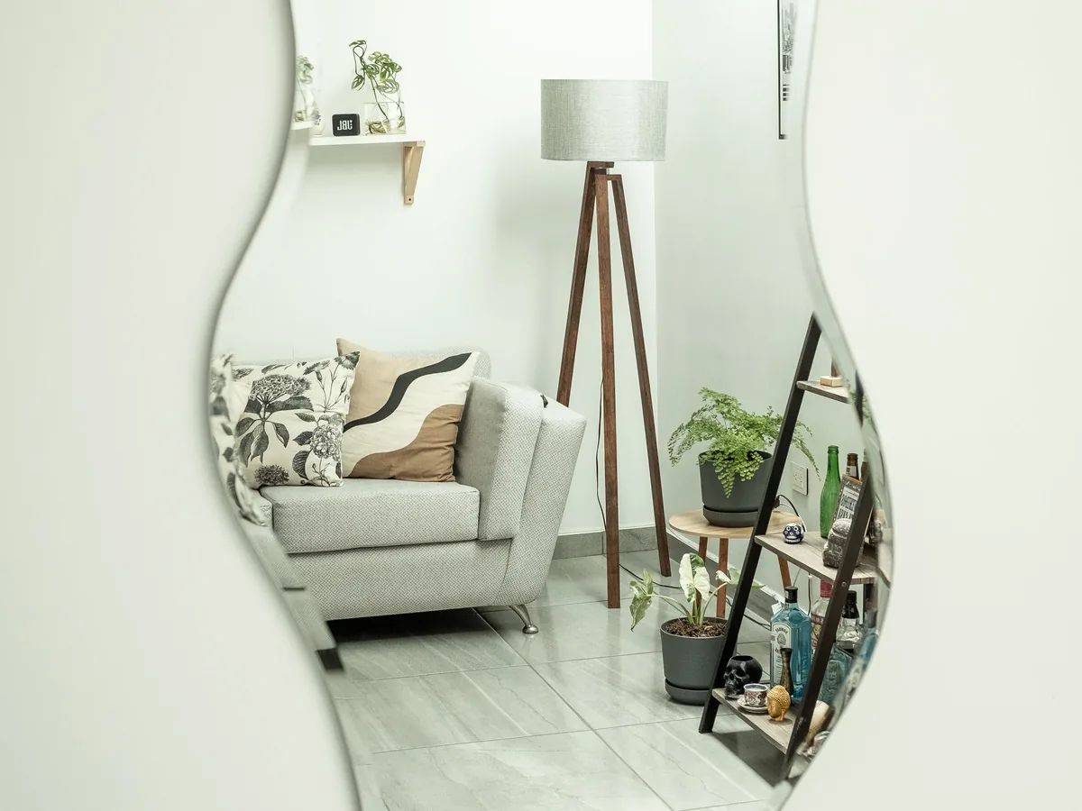 Miroir mural reflétant un canapé, une lampe et une petite table d'appoint