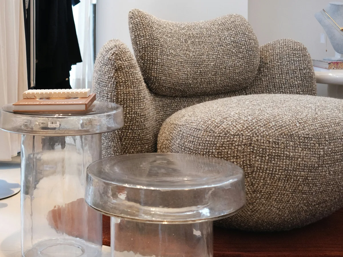 Tables d'appoint transparentes placées près d'un fauteuil dans un salon lumineux