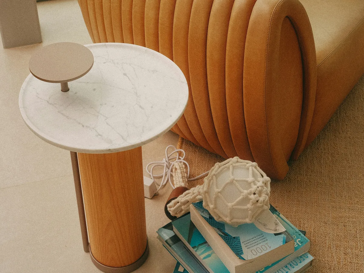 Table d'appoint en pierre claire placée devant un fauteuil brun