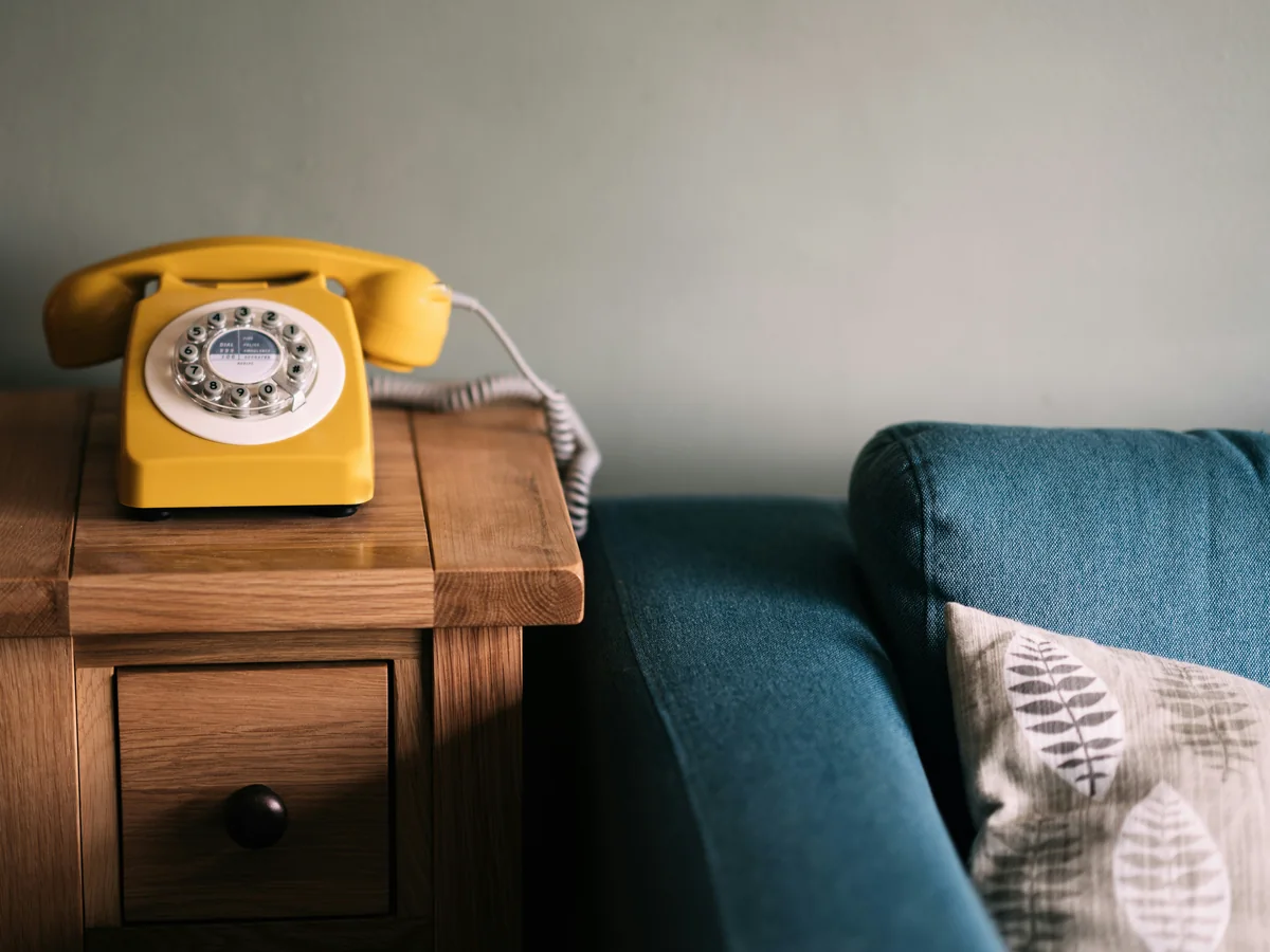 Téléphone posé sur une table d'appoint en bois contre un canapé bleu